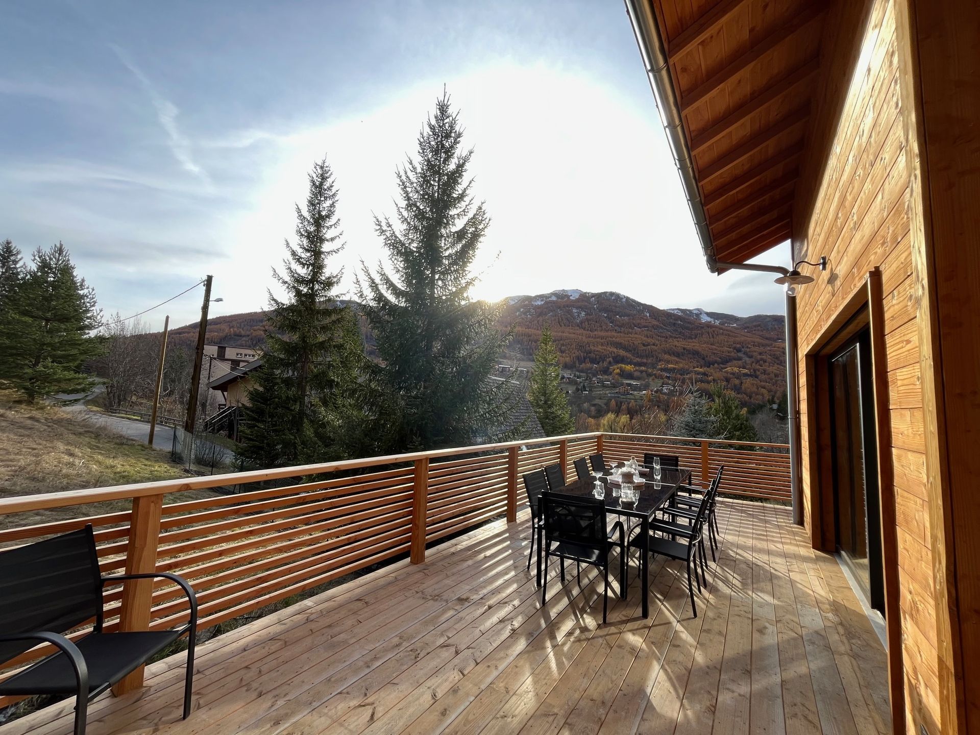 Une terrasse en bois avec une table et des chaises donnant sur un magnifique paysage de montagne.