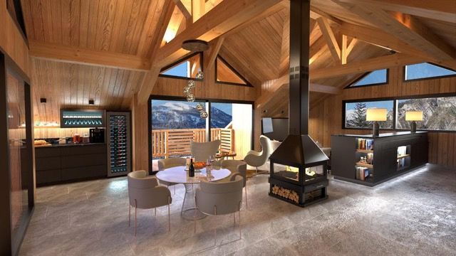 Salon avec poutres apparentes, cheminée centrale, table à manger et vue sur les montagnes.