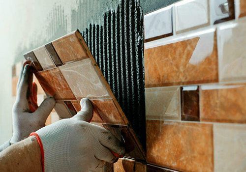 Una persona está instalando azulejos en una pared.