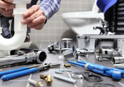 Un fontanero está arreglando una tubería del lavabo de un baño.
