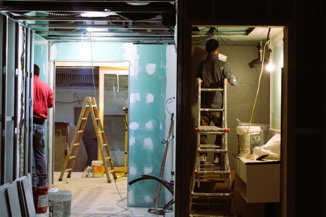 Un hombre está de pie en una escalera en una habitación en construcción.