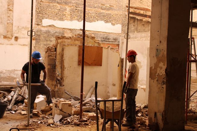 Dos trabajadores de la construcción están de pie en un edificio en construcción.