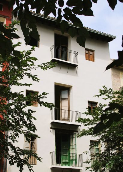 Un edificio blanco con una puerta verde y balcones.