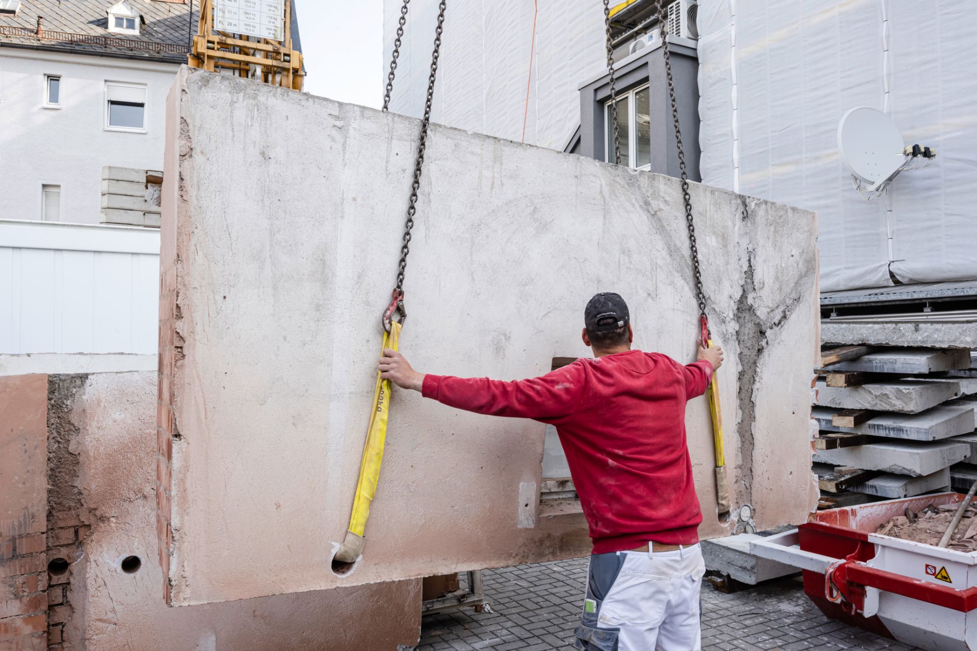 Handwerker richtet Betonfertigteil an Gebäudewand aus