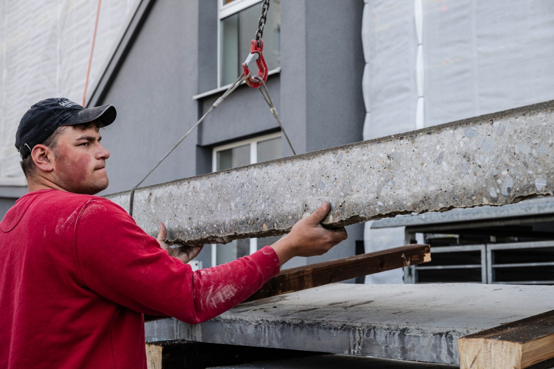 Handwerker bei Betonmontage an Gebäudefassade