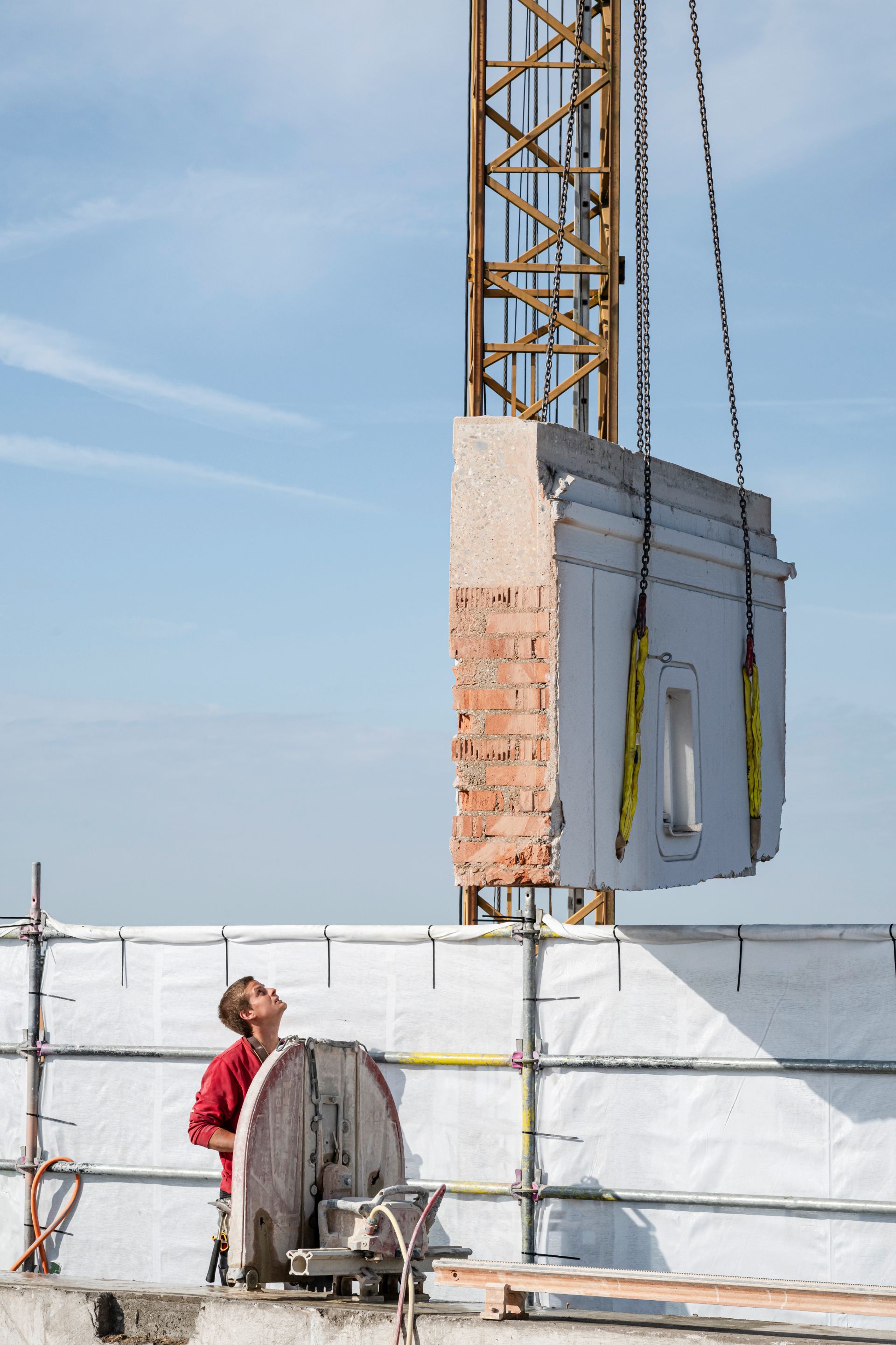 Kran transportiert Betonwand auf Mehrfamilienhaus-Baustelle