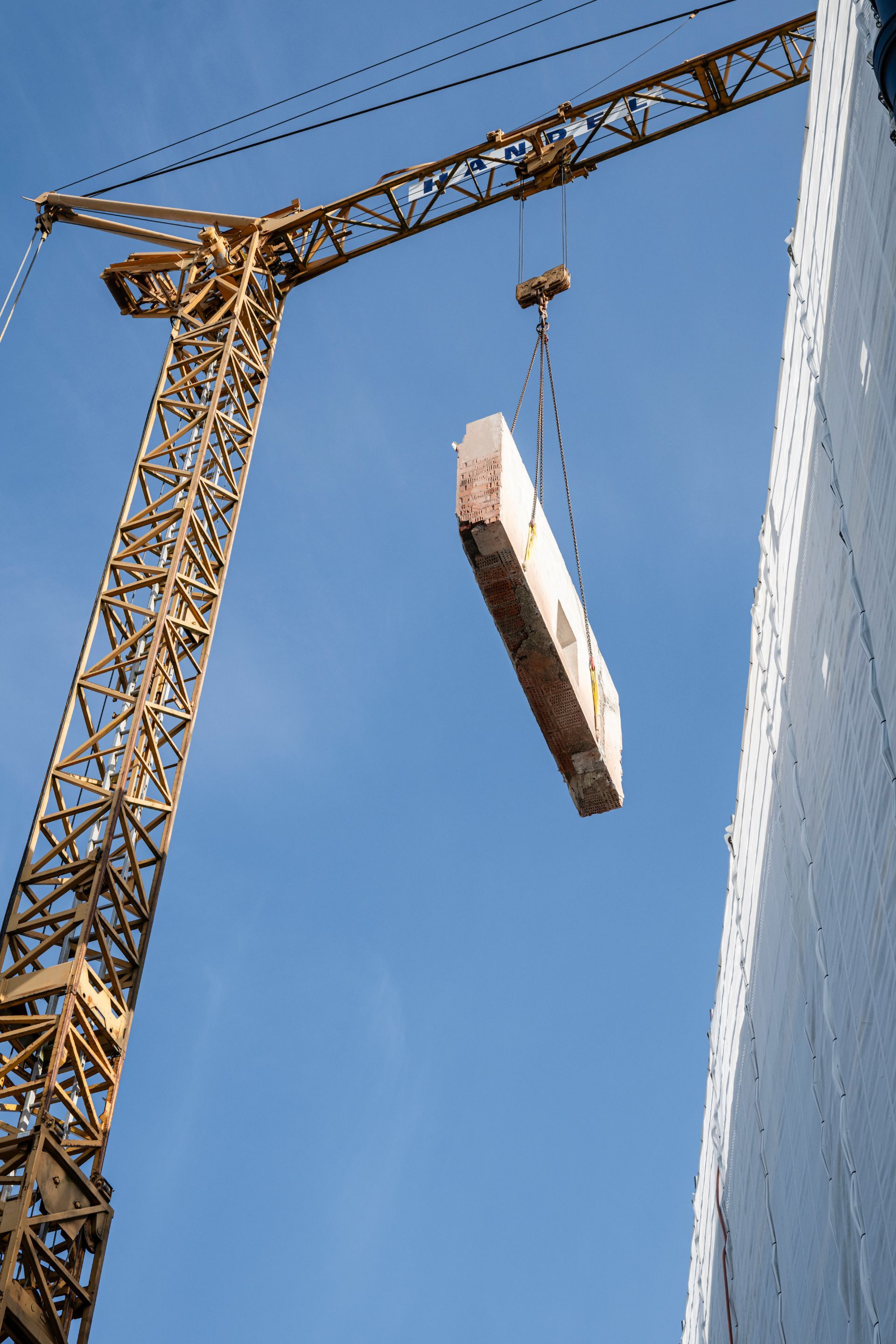 Kran setzt massives Betonelement in Wandöffnung ein