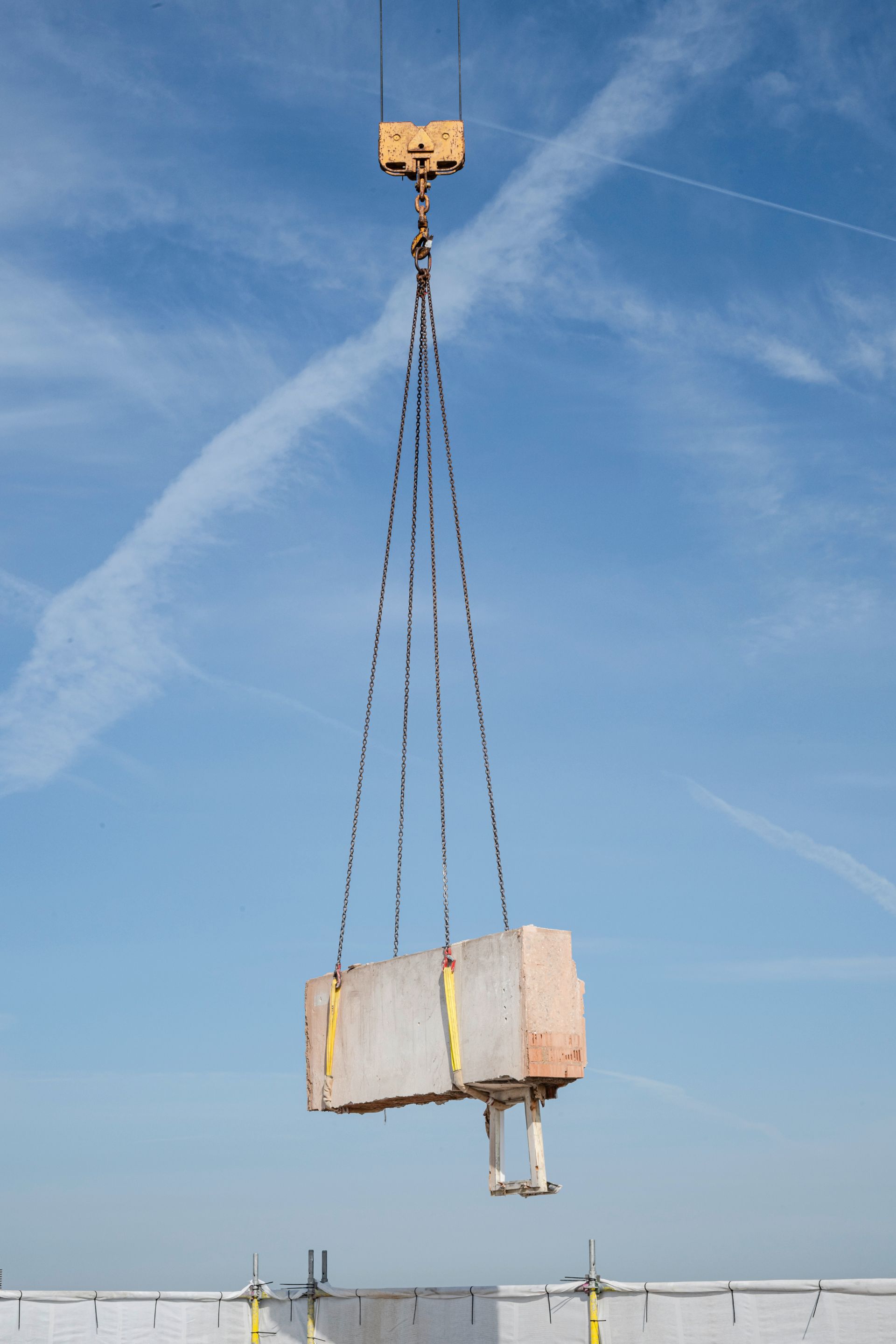 Kran transportiert Betonblock für Montage im Hochbau