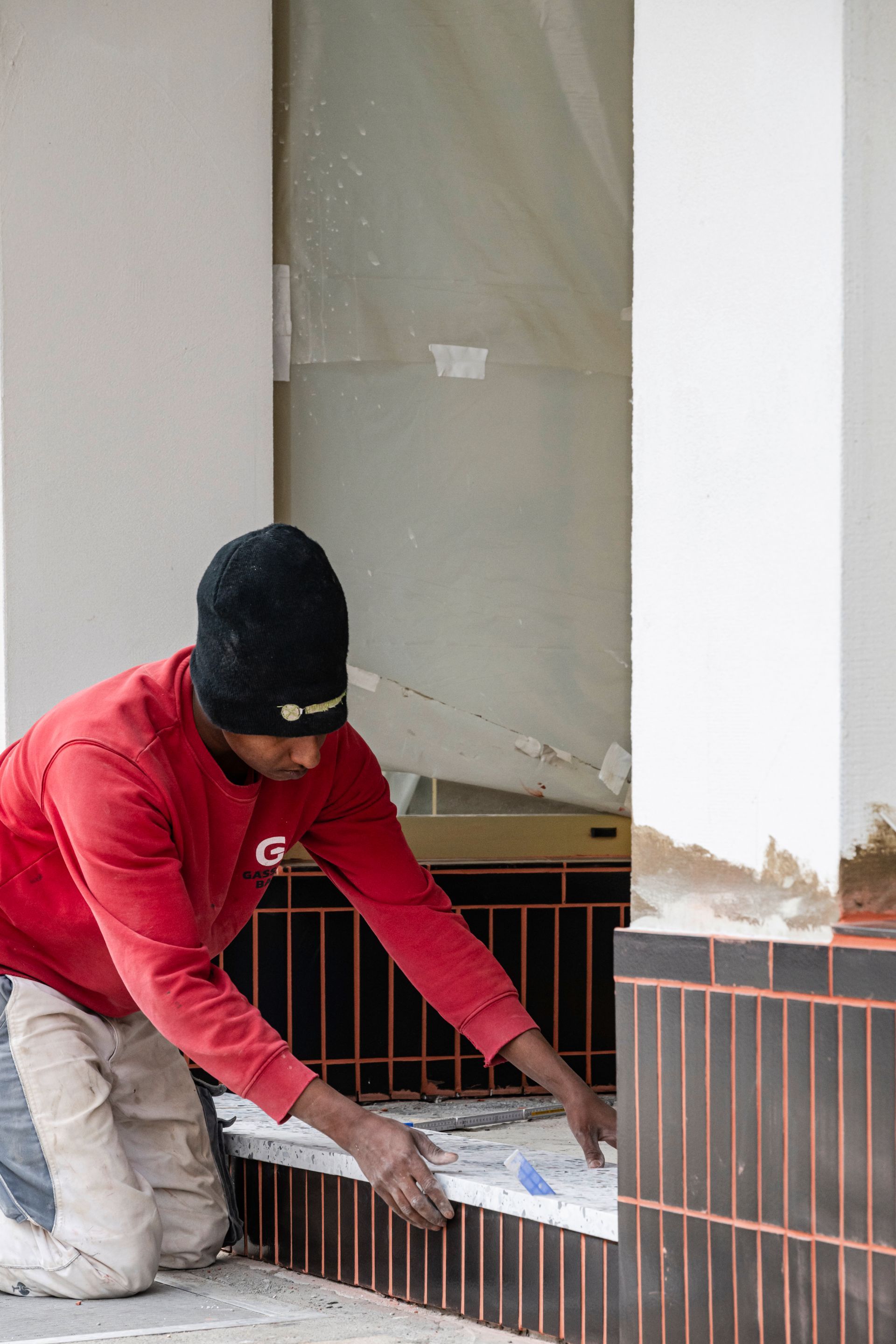 Fliesenarbeiten bei Sanierungsarbeiten an einem Geschäftsgebäude – Sockelbereich