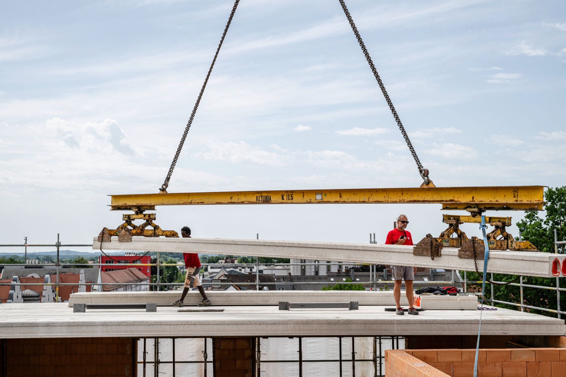 Kran hebt großes Betonelement auf Baustelle – Fertigteilmontage