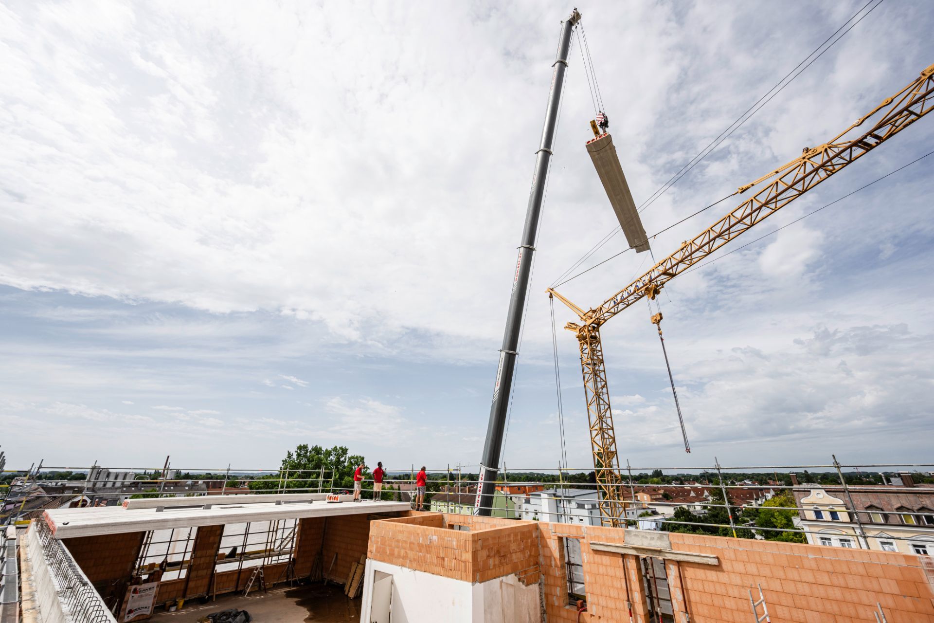 Kran hebt langes Betonelement über Baustelle für Montage