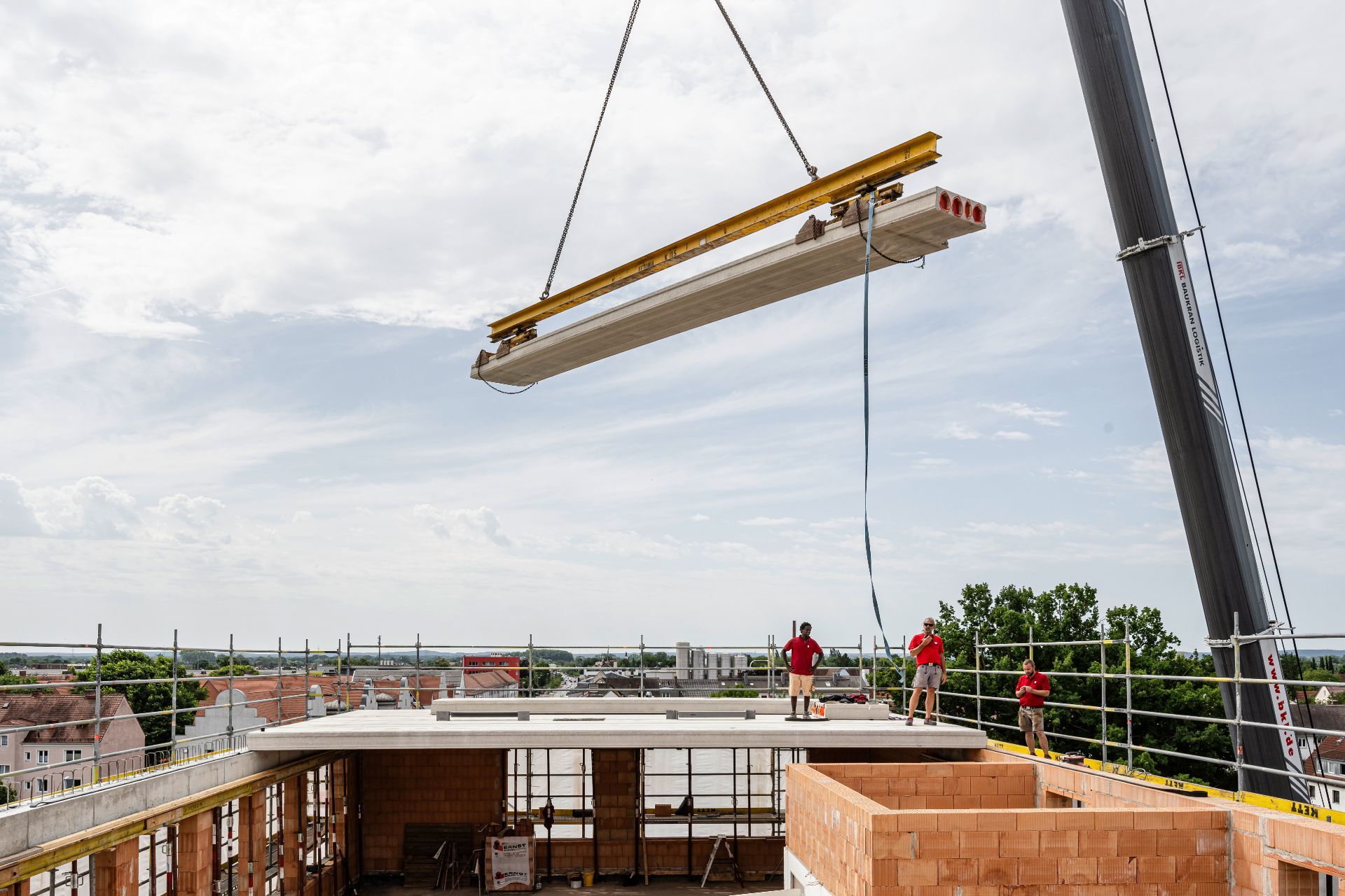Schwere Betonplatte wird hoch über der Baustelle eingehoben
