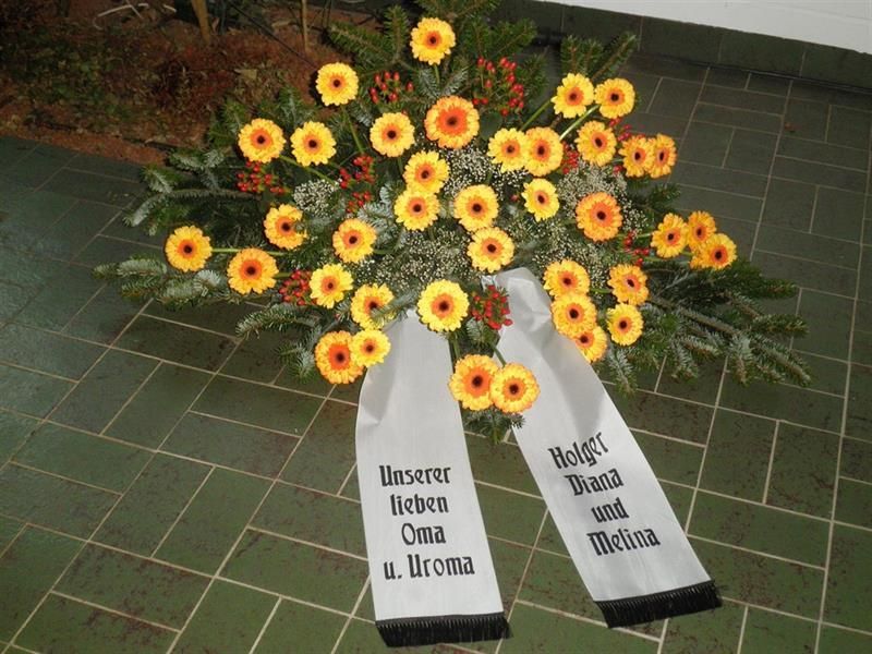 Ein Blumenstrauß mit einer Schleife mit der Aufschrift „Unsere liebe Oma“