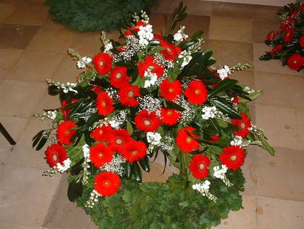 Ein Kranz aus roten und weißen Blumen liegt auf einem gefliesten Boden