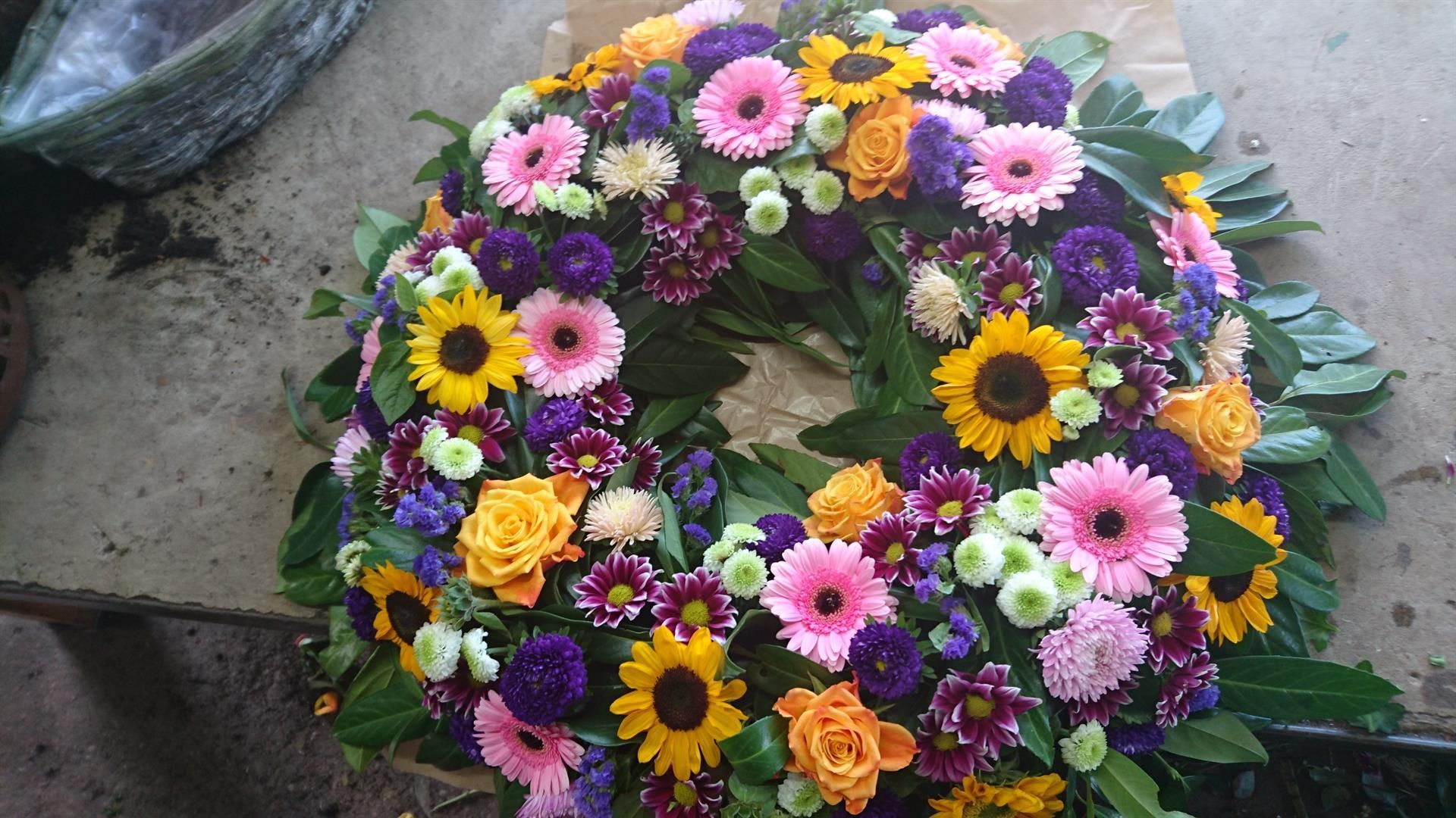 Ein Kranz aus bunten Blumen steht auf einem Tisch