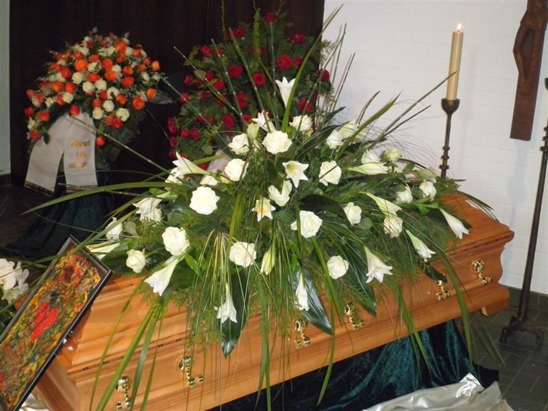 Ein Sarg ist mit Blumen und einer Kerze geschmückt