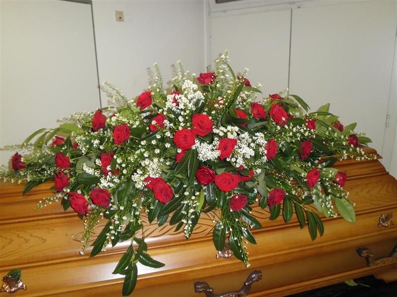 Ein Sarg ist mit roten und weißen Rosen und Schleierkraut geschmückt