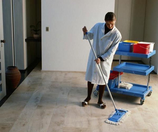 Una mujer limpiando el suelo con un trapeador