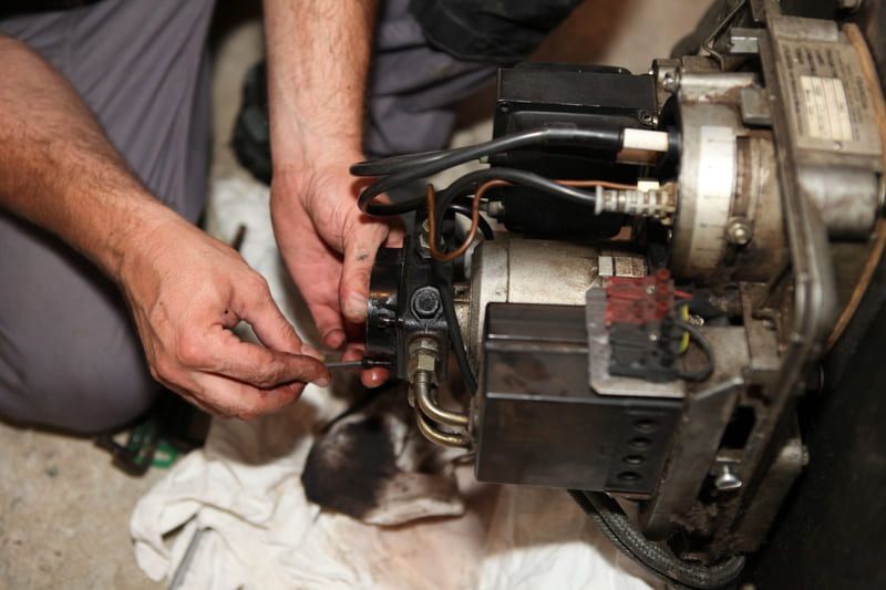 Des mains travaillent sur une machine complexe, ajustant les fils et les composants d'un appareil métallique.