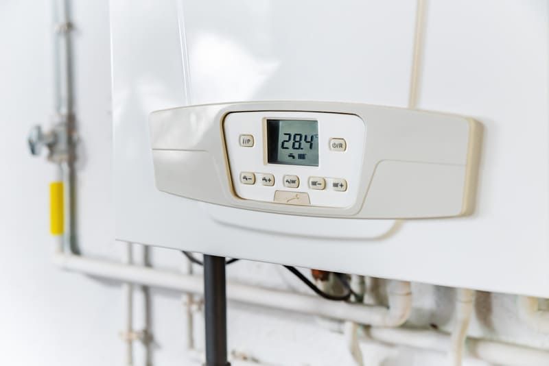 Thermostat mural de chaudière indiquant 28,4 °C sur un appareil de chauffage blanc
