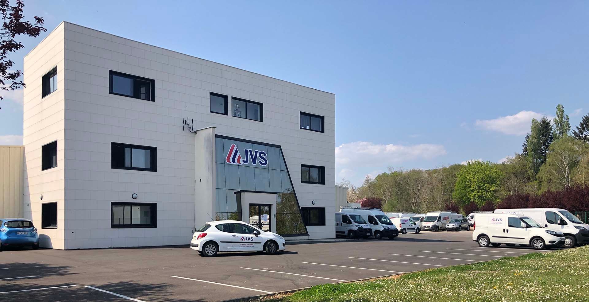 Immeuble de bureaux moderne avec parking sous un ciel bleu azur.