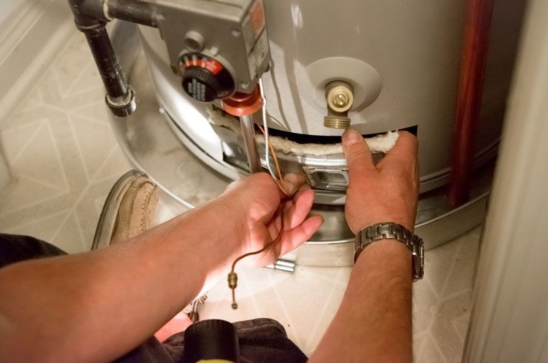 Mains ajustant la vanne d'un chauffe-eau et les raccords de tuyauterie à l'aide d'une clé