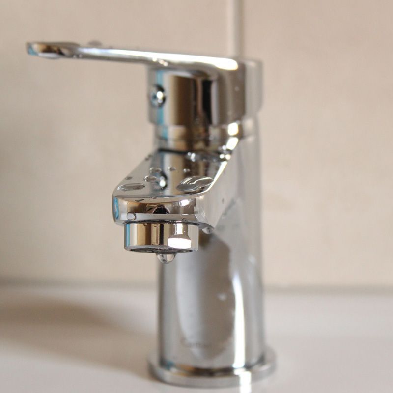 Robinet de salle de bain chromé avec poignée monocommande sur un lavabo blanc.