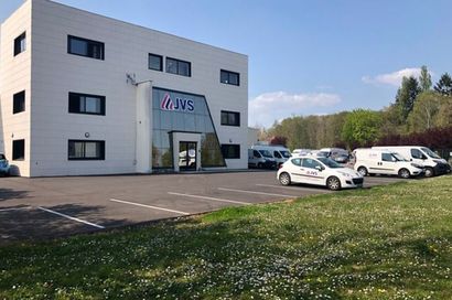 Immeuble de bureaux moderne avec voitures garées et pelouse au premier plan par temps clair
