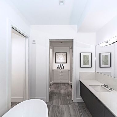 Salle de bains moderne et lumineuse, d'un blanc éclatant, avec double vasque, miroir et porte donnant sur une pièce attenante équipée d'une commode.
