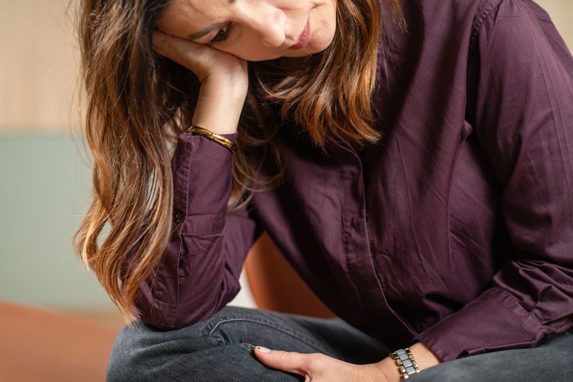 Une femme assise sur un canapé, la tête appuyée sur sa main, affiche une expression fatiguée ou pensive.