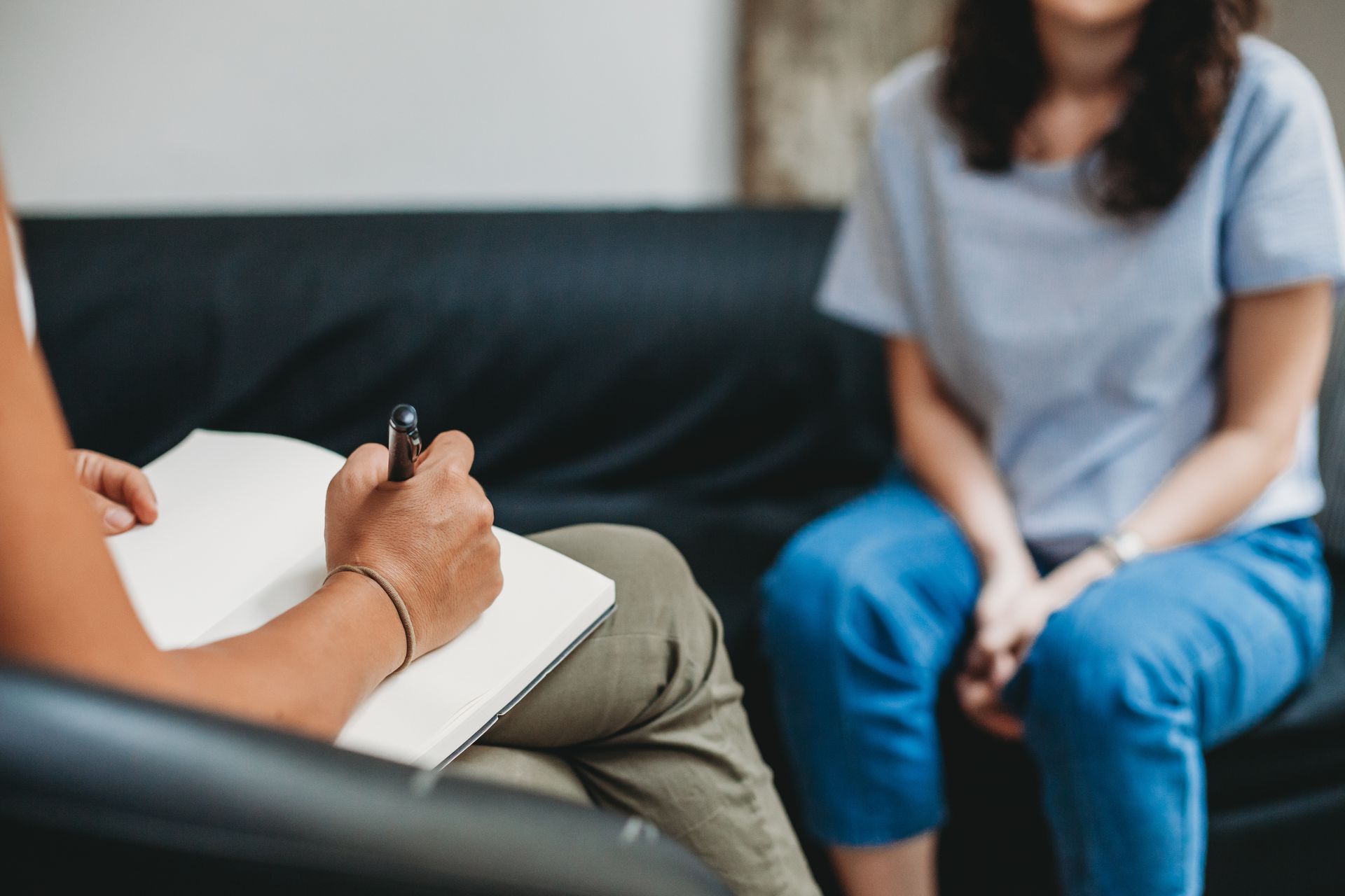 Une thérapeute assise en face d'une personne prend des notes lors d'une séance de thérapie.