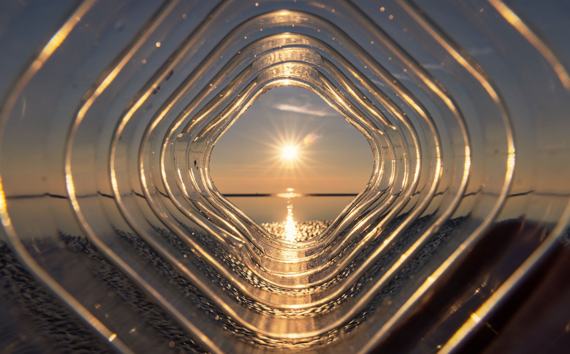 Le coucher du soleil reflété à travers des anneaux concentriques en verre ou en métal en forme de losange.