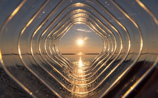 Le coucher du soleil reflété à travers des anneaux concentriques en verre ou en métal en forme de losange.