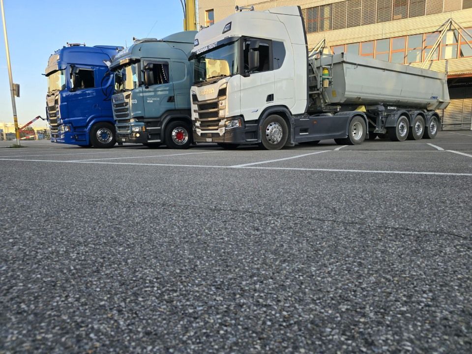 Auf einem Parkplatz stehen drei Sattelschlepper nebeneinander.