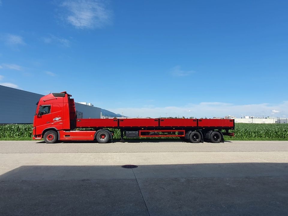 Ein roter Sattelschlepper steht am Strassenrand.