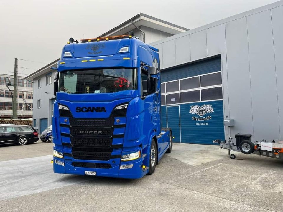 Ein blauer Scania-Lkw steht vor einem Gebäude.