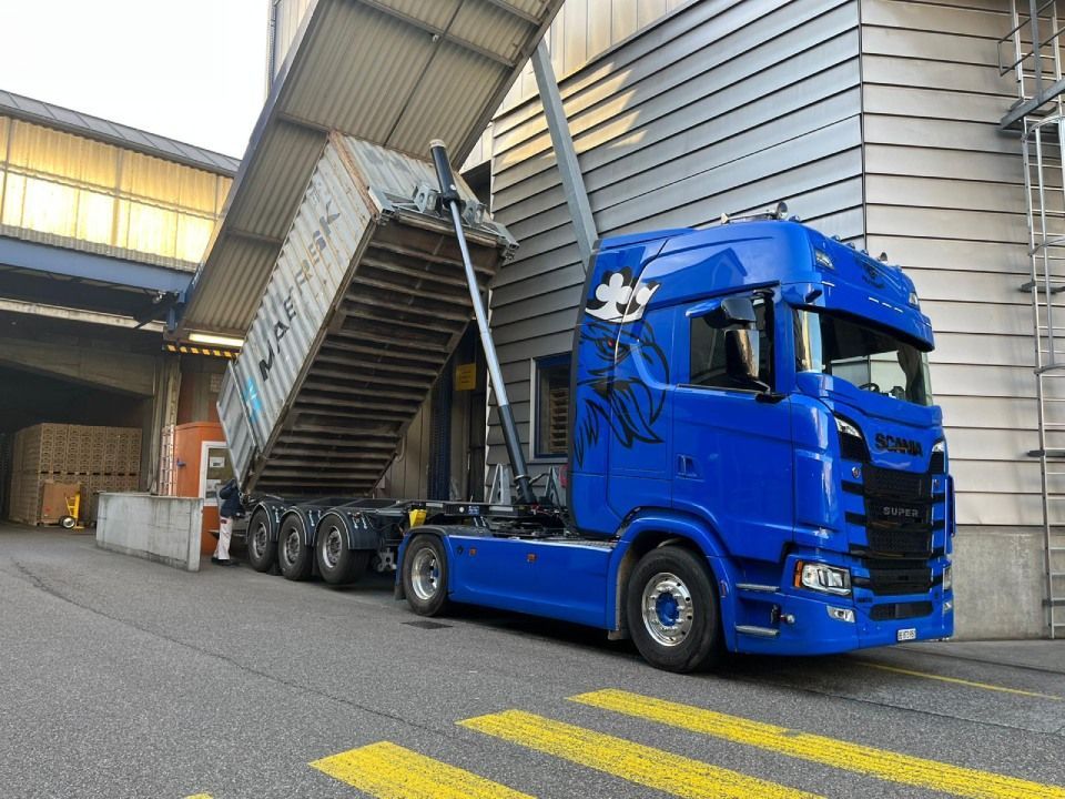 Ein blauer Sattelschlepper steht vor einem Gebäude.