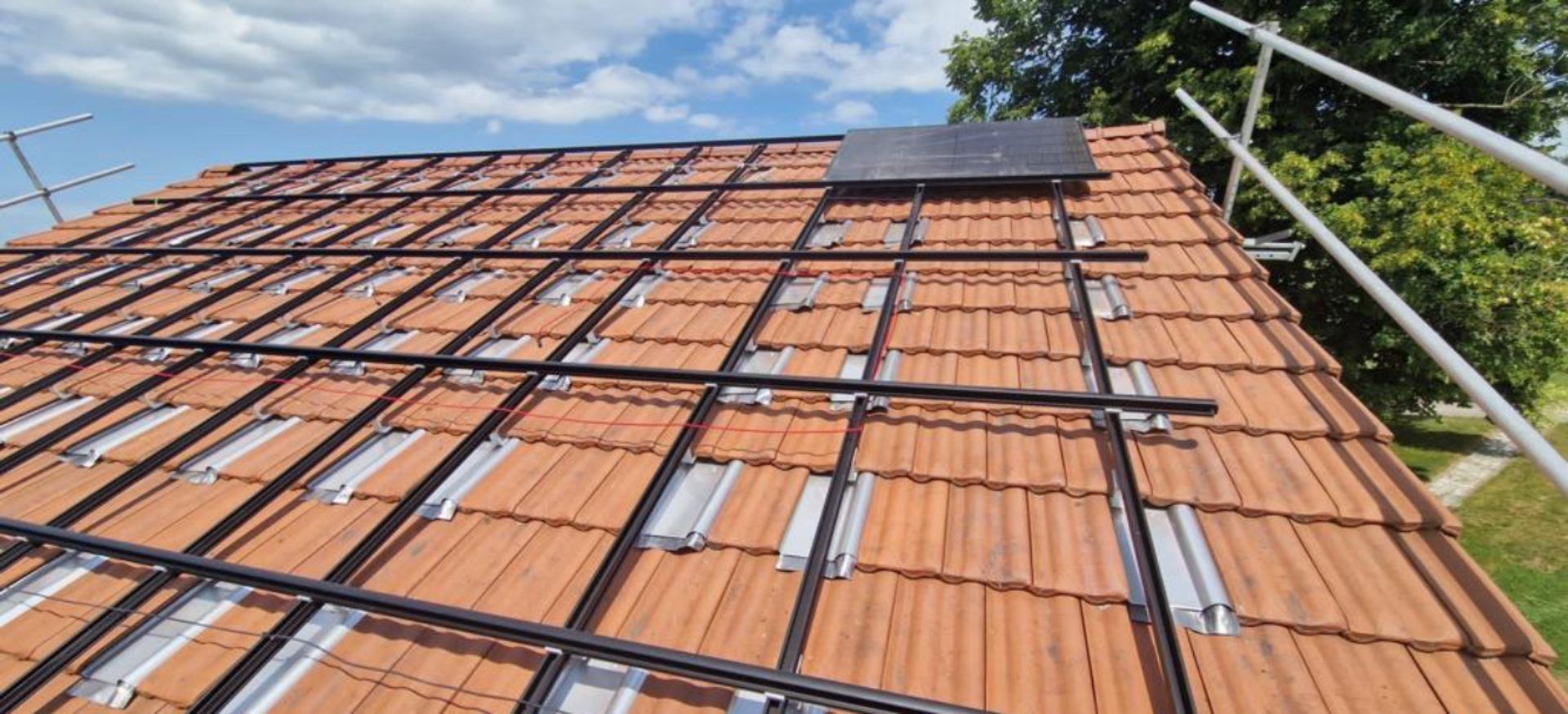 toit avec installation de tuiles métalliques et un panneau solaire accroché