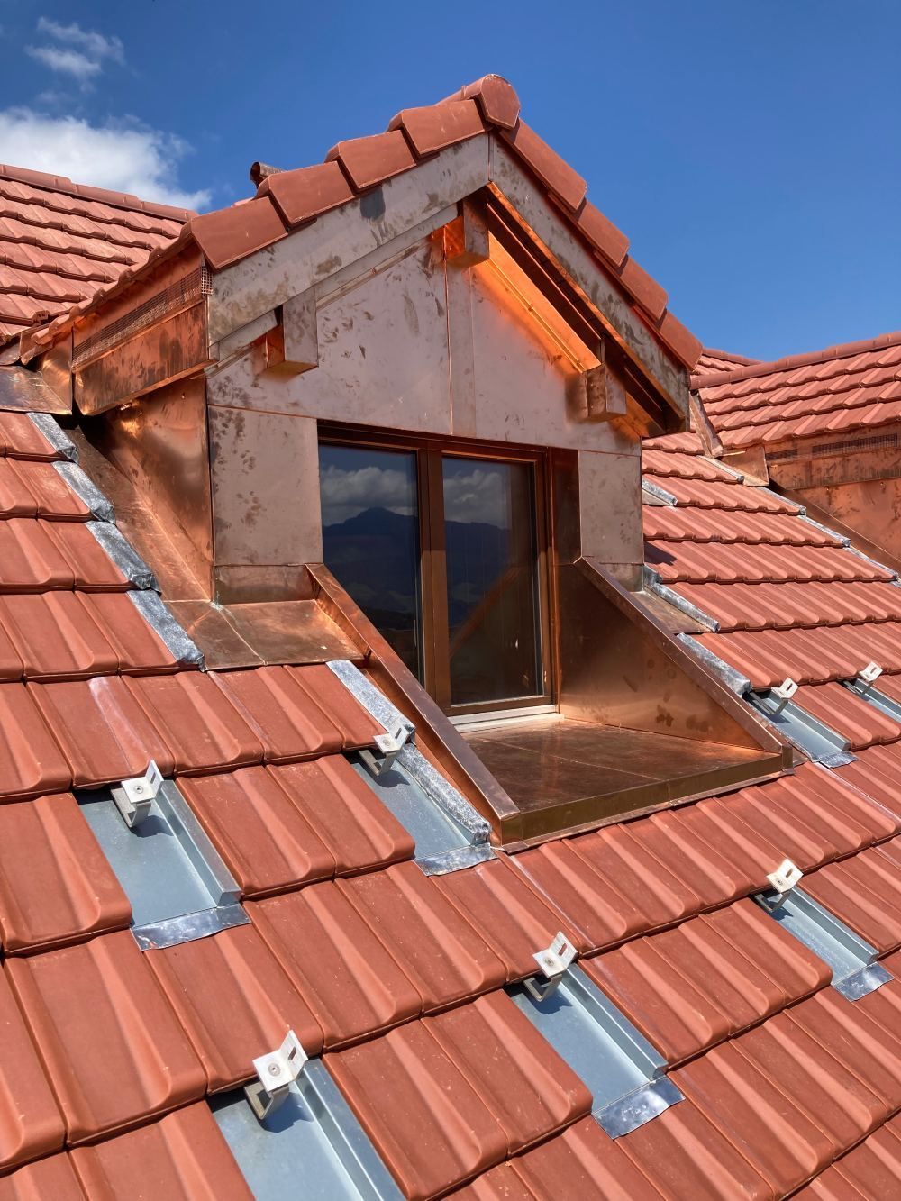 gros plan sur un toit avec des tuiles métalliques et une fenêtre