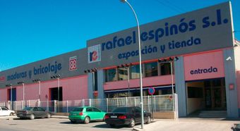 Fachada de Rafael Espiños sl, un edificio rosa y azul con coches aparcados y un letrero de entrada.