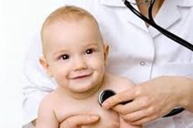 Bebé sonriente siendo examinado con un estetoscopio por un profesional de la salud.