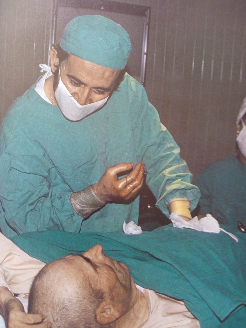 Cirujano con uniforme verde inclinado sobre un paciente, sala de operaciones.