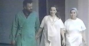 Un hombre con una bata verde y dos mujeres con ropa blanca caminando juntos, posiblemente en un pasillo de hospital.