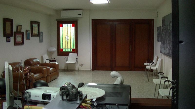 Sala de estar con sofás de cuero, un proyector y una vidriera.