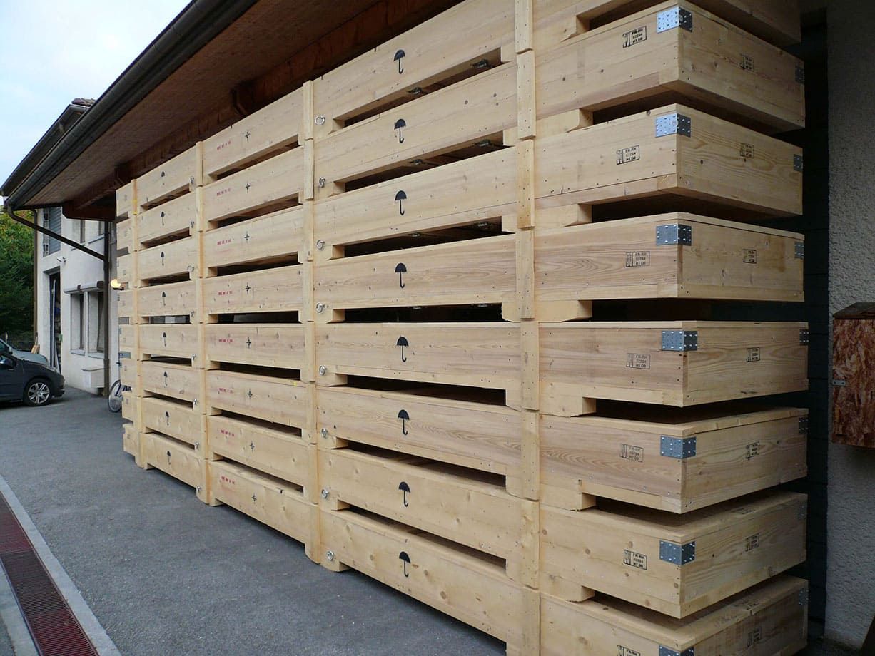 Grande pile de caisses en bois léger à fentes horizontales à côté d'un bâtiment extérieur