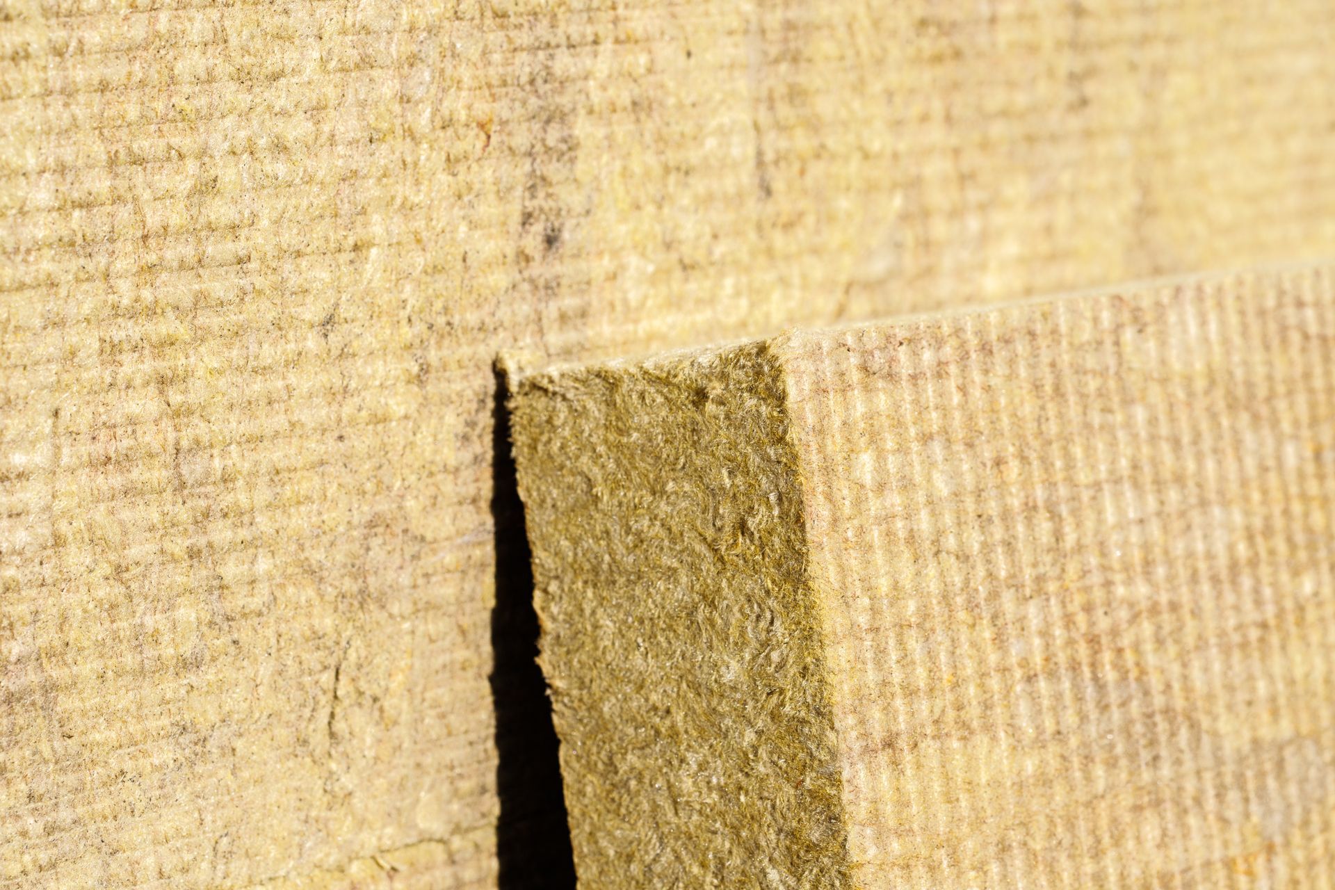 Gros plan sur un isolant en fibres de bois ; matériau fibreux brun clair à la texture visible.