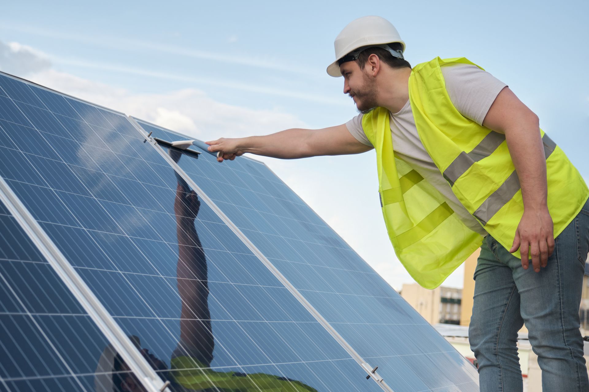 Un monsieur nettoie les panneaux solaires en surface