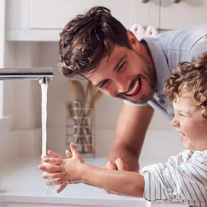Un homme qui rigole avec son enfant qui se lève les mains
