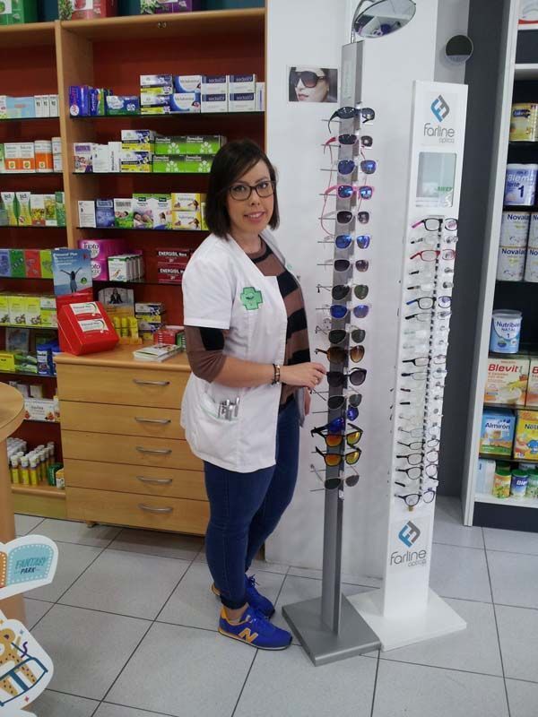 Una mujer parada junto a una exhibición de gafas de sol en una farmacia.