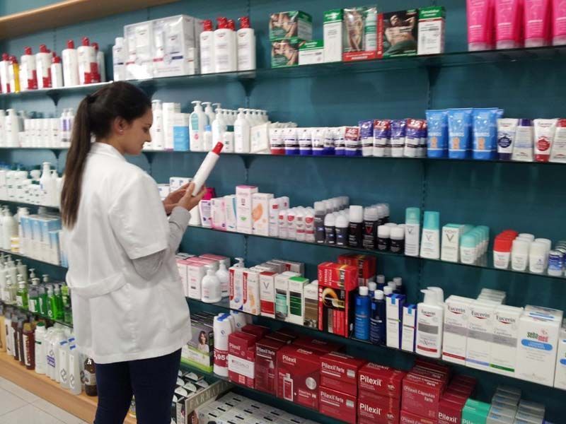 Una mujer está mirando una botella de loción en una farmacia.